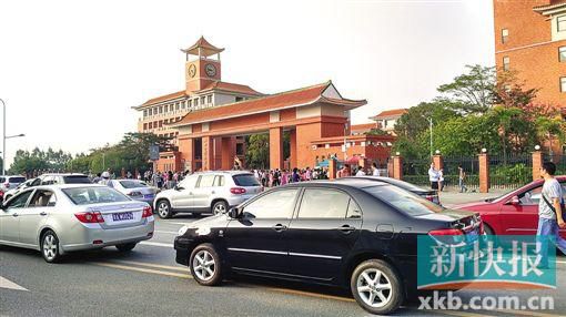 學(xué)校門口的路段停滿前來(lái)接送孩子的車輛,不少家長(zhǎng)在校門口等候。